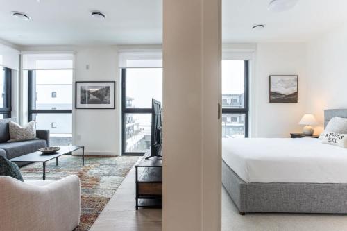 a white bedroom with a bed and a couch at Alpine Living - Modern 2 Bedroom Condo in Revelstoke