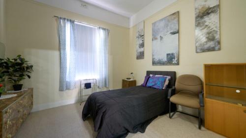 a bedroom with a bed and a chair and a window at Squatters Cottage in Port Augusta