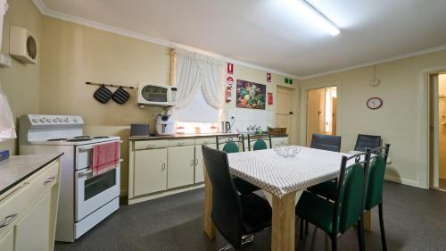 a kitchen with a table and chairs and a kitchen with a stove and oven at Squatters Cottage in Port Augusta