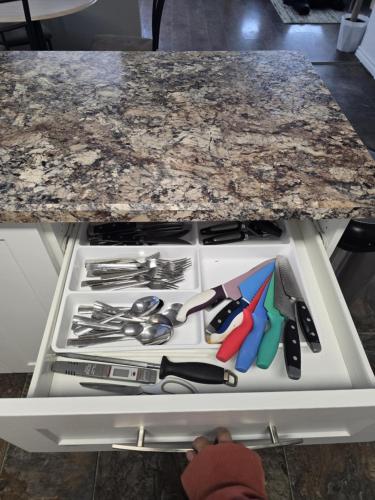 a counter top with a bunch of utensils in a drawer at Like Home in Regina