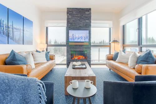 a living room with couches and a fireplace at The View - Luxury Penthouse Condo in Revelstoke