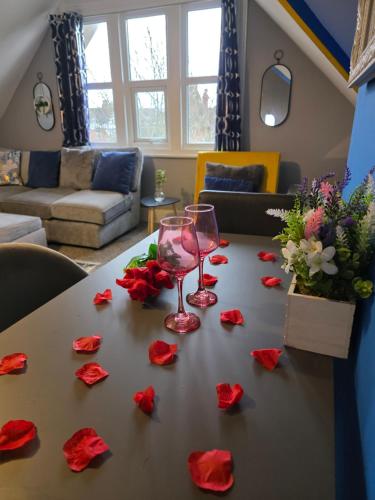 a table with two wine glasses and red roses on it at Vibrant - Free Parking - Sleeps 6 M20-FolkestoneCentralStation in Folkestone