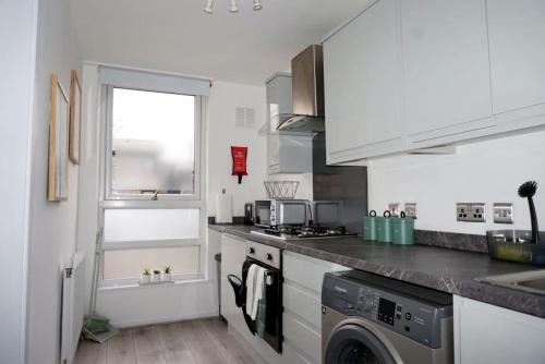a kitchen with a washing machine and a window at Peckham City Vibes 2BR with Wi-fi and Balcony in London
