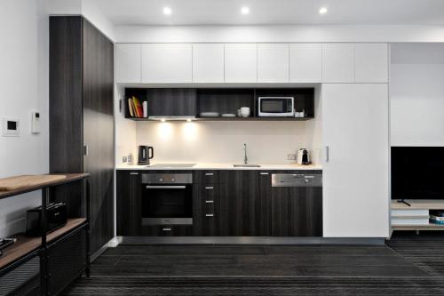 a kitchen with black and white cabinets and a microwave at A tale awaits - just steps from trendy cafés and lively bars in Melbourne