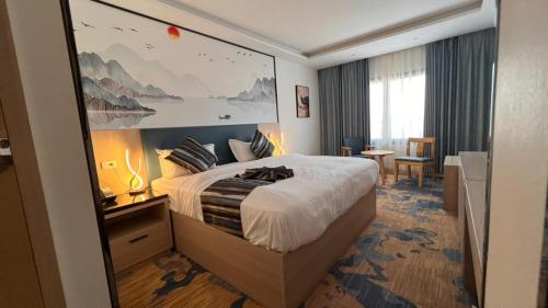 ein Hotelzimmer mit einem Bett und einem großen Gemälde an der Wand in der Unterkunft Marigold Tripoli hotel فندق ماري قولد in Tripoli