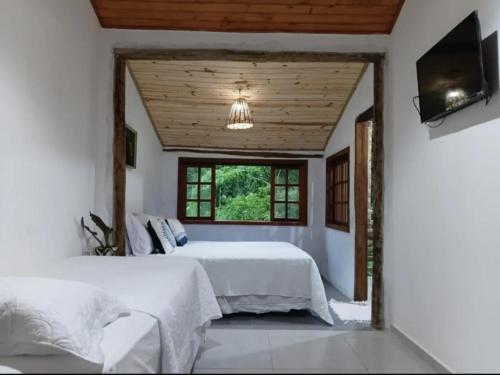 a bedroom with two beds and a flat screen tv at Loft 01 encanto dos ipês in Paraty