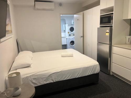 a small room with a bed and a refrigerator at Bondi Beach Studios Suite in Sydney