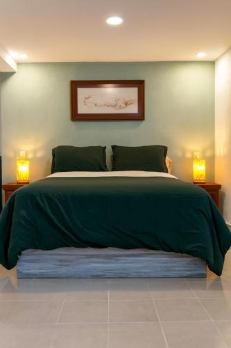 a bedroom with a large green bed with two lamps at Casa Centenario in Taxco de Alarcón