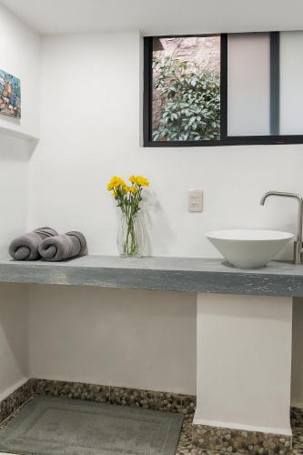 a bathroom counter with a sink and a vase of flowers at Casa Centenario in Taxco de Alarcón