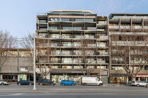 a large building with cars parked in a parking lot at A tale awaits - just steps from trendy cafés and lively bars in Melbourne