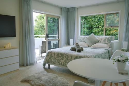 a bedroom with a bed and a table and a window at Welcome Bay Heights in Tauranga