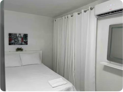 een witte slaapkamer met een bed en een televisie bij Shalex House in Carolina