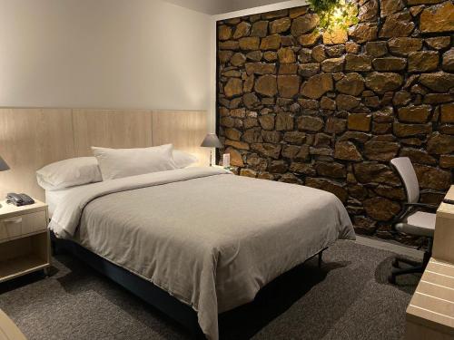 a bedroom with a large bed and a stone wall at Hotel La Villa Mollendo in Mollendo