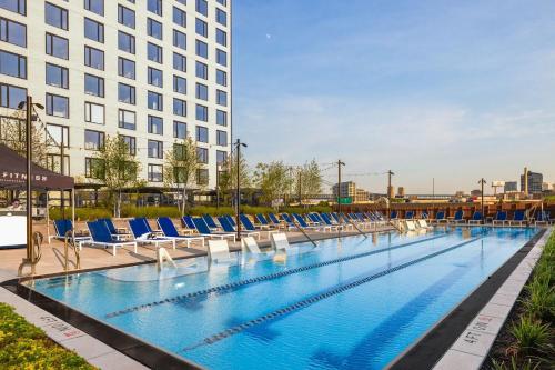 a large swimming pool with blue chairs and a building at Luxury Apartments by Hyatus at Central Philly in Philadelphia
