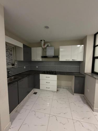 a large kitchen with white cabinets and a tile floor at Elite Corners Luxury 2BR Apartment The Gate Mall Faisal Town in Barkat