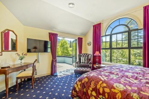 a bedroom with a bed and a desk and a window at Fontainebleau Luxury B&B in Hanmer Springs