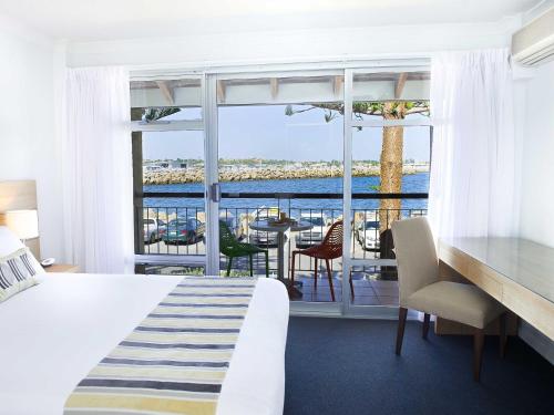 a bedroom with a bed and a view of the ocean at Be. Fremantle in Fremantle
