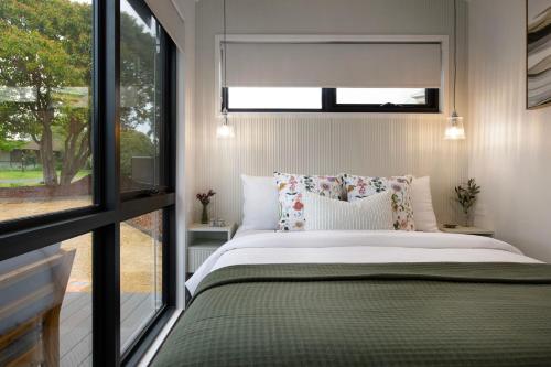 a bedroom with a bed and a window at Piccola Verde Tiny House in Hepburn