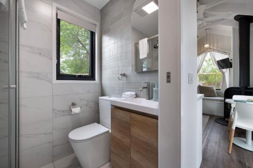 a white bathroom with a toilet and a sink at Piccola Verde Tiny House in Hepburn