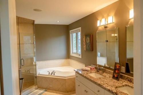 ein Badezimmer mit zwei Waschbecken, einer Badewanne und einer Dusche in der Unterkunft The Bards Roost - 3BR King Ensuite Family Friendly in Stratford