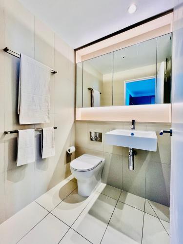 a bathroom with a toilet and a sink and a mirror at High Rise CBD Apartment with Amazing Views, 3 beds, Gym,SPA & Pool, Easy Transport in Melbourne