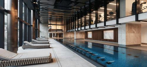 a swimming pool in a building with chairs around it at High Rise CBD Apartment with Amazing Views, 3 beds, Gym,SPA & Pool, Easy Transport in Melbourne