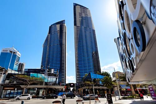 two tall buildings in a city with parked cars at Circle on Cavill 2, 3, 4 & 5 Bedroom SkyHomes & SUB PENTHOUSES by Gold Coast Holidays in Gold Coast