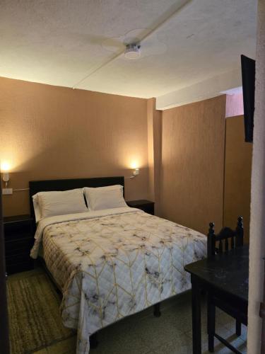 a bedroom with a bed and a table in it at Hotel Fontana Real in Quetzaltenango
