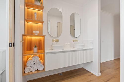 a bathroom with two sinks and two mirrors at Pelican Lake Holiday House in Merimbula