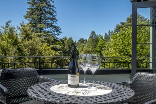 a bottle of wine sitting on a table with two glasses at Fontainebleau Luxury B&B in Hanmer Springs