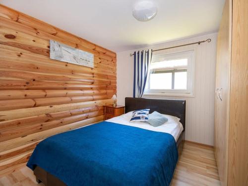 a bedroom with a wooden accent wall and a bed at Comfortable holiday homes, jacuzzi, summer pool in Łacko