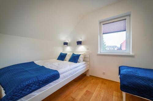 a bedroom with a bed with blue pillows and a window at Holiday homes with pool, close to the beach in Rewal