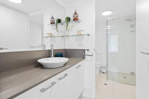 a white bathroom with a sink and a shower at Unit 2 Point Break in Yaroomba