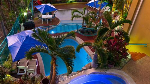 an overhead view of a pool with palm trees and umbrellas at Toscana Village Resort in Airlie Beach