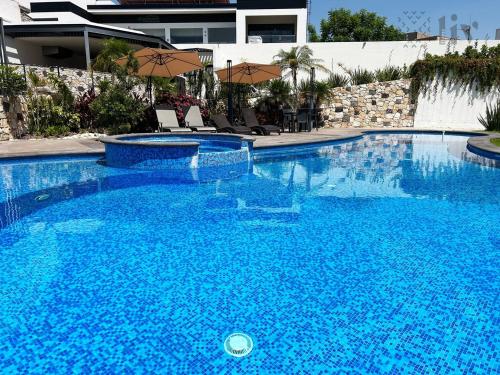 a large blue swimming pool with chairs and umbrellas at Private Suite with bathroom and top amenities in La Cañada