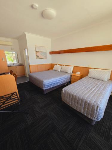 a hotel room with two beds and a chair at Lakes Entrance RSL Glenara Motel in Lakes Entrance