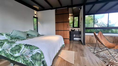 a bedroom with a bed and a chair at Cabaña en el Lago Cerca MetroCable ARVI in Guarne