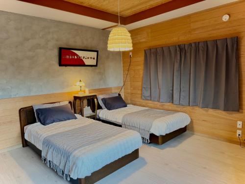 a bedroom with two beds and a window at 愛犬と泊まれる宿 ほこほこsaza 一棟貸し 海も川も徒歩圏内 dog run付き 釣りの穴場 サーフィン 自然 満点星空 蛍鑑賞 最大7名 in Miyazaki