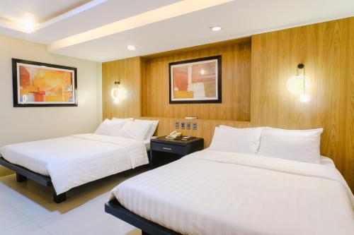 two beds in a hotel room with wooden walls at O Hotel in Bacolod