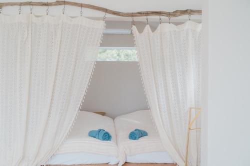 a bed with white curtains next to a window at furaha in Iwamicho