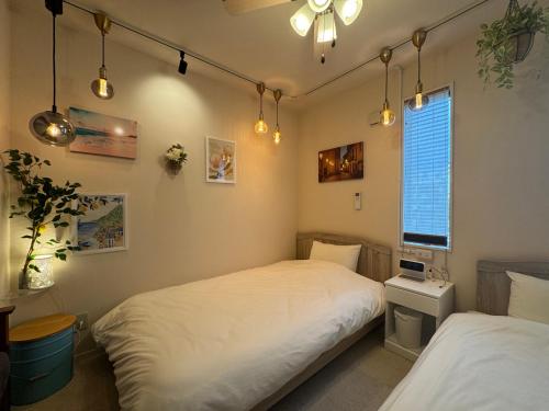 a bedroom with two beds and a window at Lhouseー遊べる宿ビリヤード 大型スクリーン 岡山駅徒歩15分 in Okayama