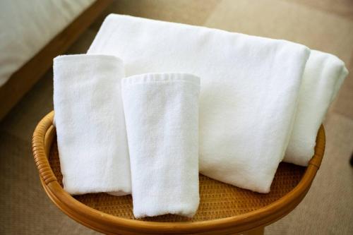 two white towels are sitting in a basket at villa itsutsu in Kamigotō