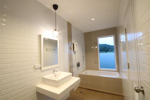 a white bathroom with a sink and a tub and a window at Greenery Hill in Ban Nok