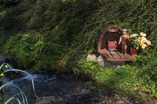 a statue of a man standing next to a small house next to a stream at Penzión Banská Klopačka in Hnilčík