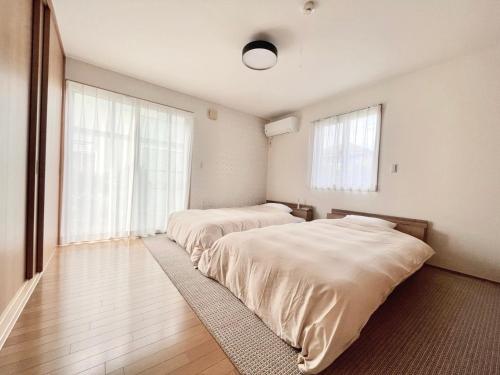 two beds in a room with two windows at 9Stay市原 in Ichihara