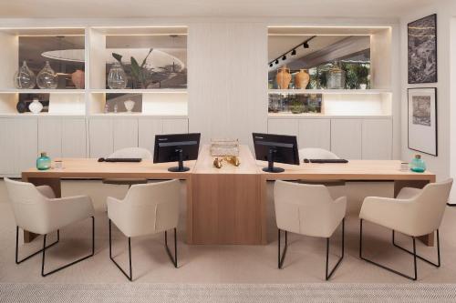 an office with two desks and white chairs at Melia Lebreros in Seville