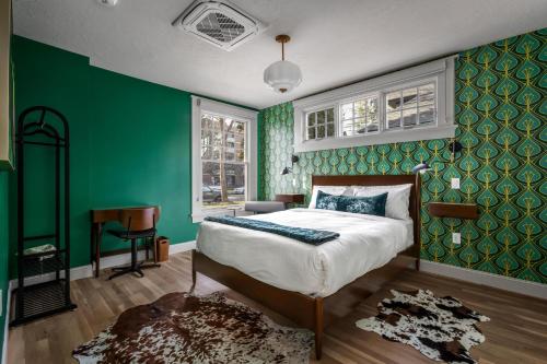 a bedroom with green walls and a bed and a desk at Assemble Boise in Boise