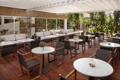 a restaurant with tables and chairs and windows at Melia Lebreros in Seville
