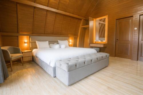 a bedroom with a large bed and a chair at PULAU LIMA Resort in Serang