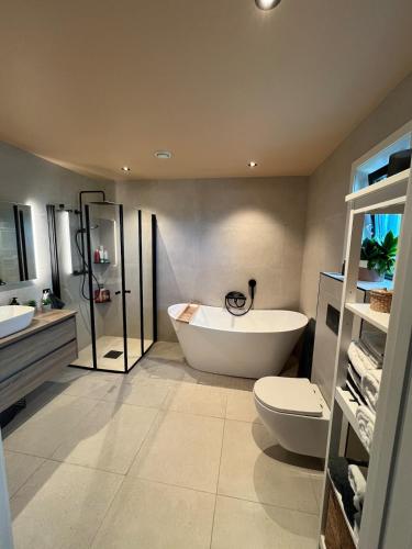 a bathroom with a tub and a toilet and a sink at Bausje Beach House in Farsund